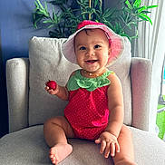 Zaya joined the competition — help win amazing prizes! baby, chair, child, clothing, cozy, cute, fruit, greenery, happy, hat, indoor, infant, natural_light, person, plant, portrait, sitting, smiling, strawberry, strawberry_outfit