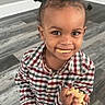 Demik joined the competition — help win amazing prizes! child, toddler, smiling, animal_crackers, food, snack, plaid_shirt, pigtails, hair, floor, wooden_floor, indoor, person, cute, happy, holding, standing, face, eyes, mouth