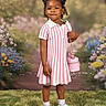 child, girl, portrait, pink_dress, striped_clothing, purse, crocs, shoes, grass, flowers, background, outdoor, standing, happy, cute, fashion, accessory, smiling, hair, young