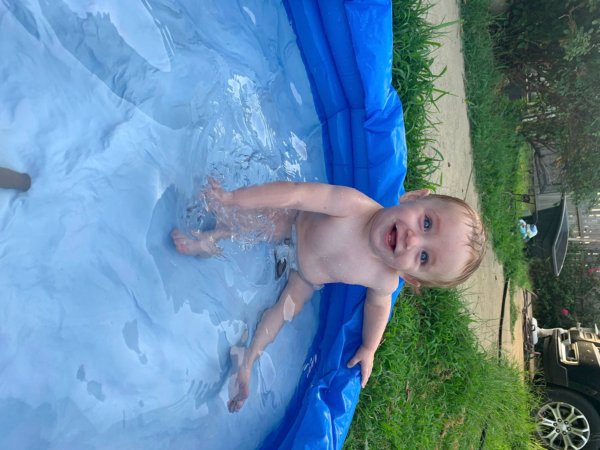 Corbin is registered to the contest to win money with this photo: arm, bathing, child, electric_blue, fun, grass, happy, joy, leisure, people_in_nature, person, plant, play, recreation, smile, swimwear, tire, toddler, tree, water