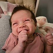 Gracelynn is registered to the contest to win money with this photo: baby, blanket, chair, clothing, cushion, cute, expression, face, fist, hair, hand, happy, indoor, infant, joy, newborn, person, pink_shirt, portrait, smiling