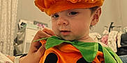 Gracelynn joined the competition — help win amazing prizes! baby, child, costume, pumpkin, orange, hat, green_leaves, face, indoor, person, cute, portrait, hand, clothing, smile, baby_clothes, infant, soft_texture, cozy, room