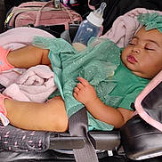 Patience is registered to the contest to win money with this photo: accessory, baby, blanket, bottle, car_seat, child, clothing, cute, footwear, headband, indoors, infant, mint_green_dress, peaceful, person, pink_shoes, resting, seat_belt, sleeping, toddler