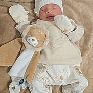 Mathias a rejoint le concours — aidez-le/la à gagner de superbes lots ! baby, sleeping, infant, plush_toy, lion, blanket, mittens, hat, soft, cozy, clothing, cute, newborn, patterned_pants, striped_socks, furry, resting, indoor, portrait, child