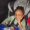 Khani is registered to the contest to win money with this photo: blanket, car_interior, car_seat, casual, child, clothing, curly_hair, indoor, person, portrait, relaxed, resting_hand, safety, seat, seatbelt, sitting, snack, thoughtful, young_child, young_person
