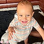 Kairo is registered to the contest to win money with this photo: baby, black_blanket, bright, brown_leather_couch, carpet, child, cute, furniture, happy, home, hooded_romper, indoor, person, playtime, plush_toy, portrait, smiling, standing, striped_clothing, toddler