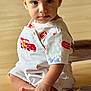 toddler, child, baby, sitting, indoor, overalls, lightning_mcqueen, foot, hand, curious, expression, floor, cushion, pattern, clothing, person, portrait, cute, toy_car, young_child