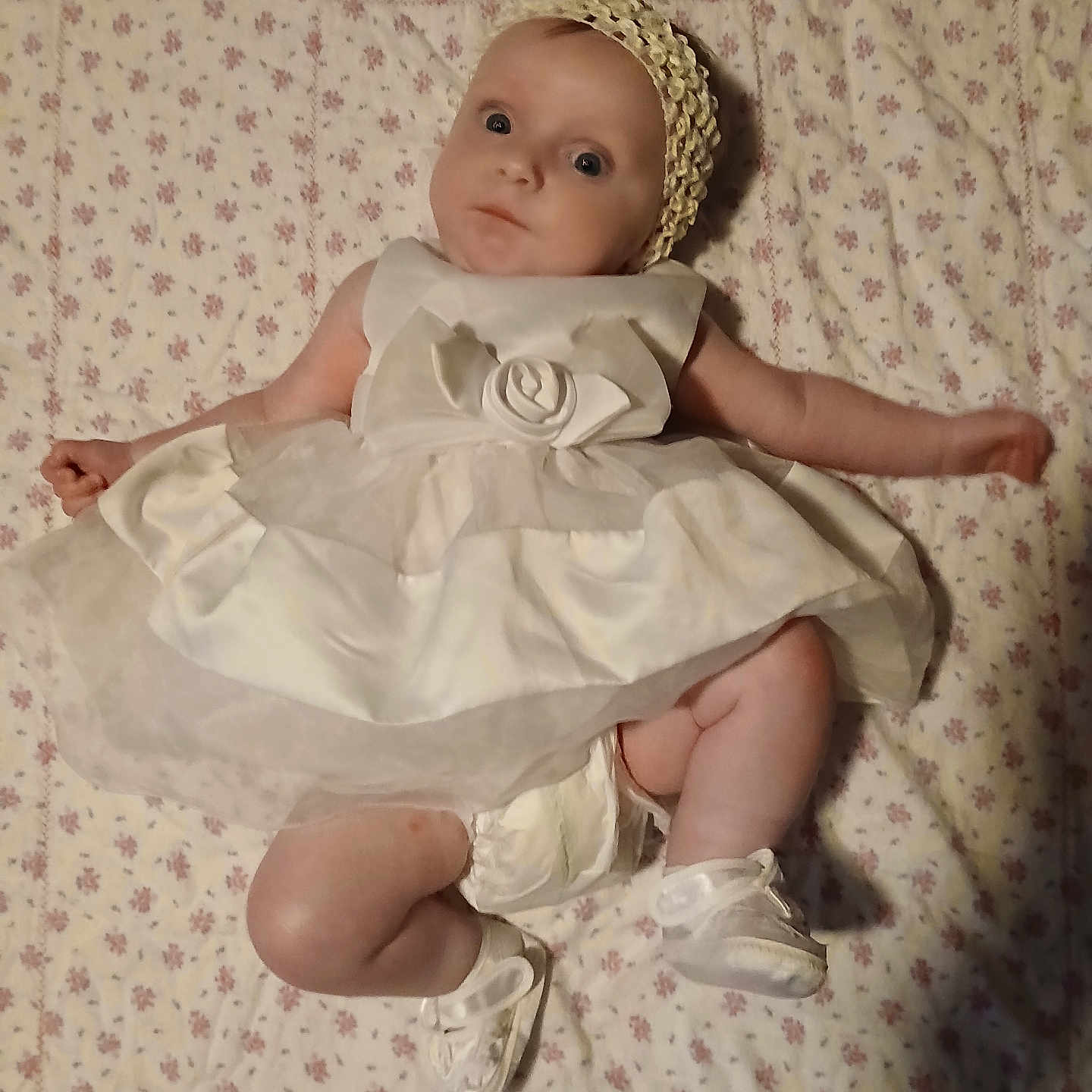 Jazman is registered to the contest to win money with this photo: baby, blanket, child, chubby, curious, cute, dress, floral, headband, indoors, infant, lying_down, pattern, person, portrait, shoes, small_footwear, soft_lighting, white_clothing, young_child