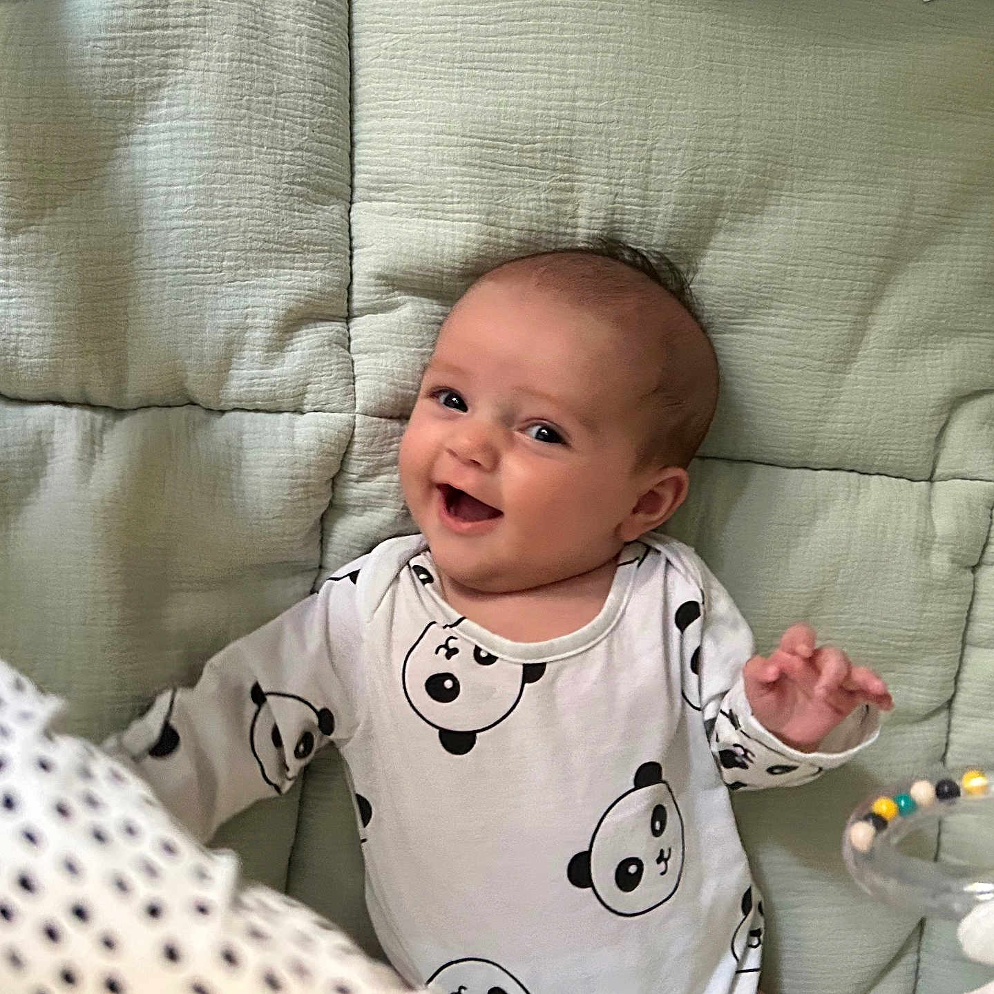 Ryta participe au concours pour gagner de l'argent avec cette photo : baby, cheerful, child, colorful, cute, expression, face, hand, happy, indoors, infant, lying_down, onesie, panda_print, playing, quilted_surface, smiling, soft_texture, toy, young