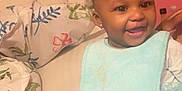 Alayah joined the competition — help win amazing prizes! baby, child, smiling, indoor, bed, pillow, blanket, clothing, hair_clip, bib, face, person, happy, toddler, cute, furniture, home, infant, sitting, cozy
