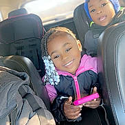 Khalani is registered to the contest to win money with this photo: child, children, car, car_seat, smiling, beanie, braided_hair, beads, jacket, seatbelt, backseat, portrait, happy, indoor, person, young, family, warm_clothing, toy, play