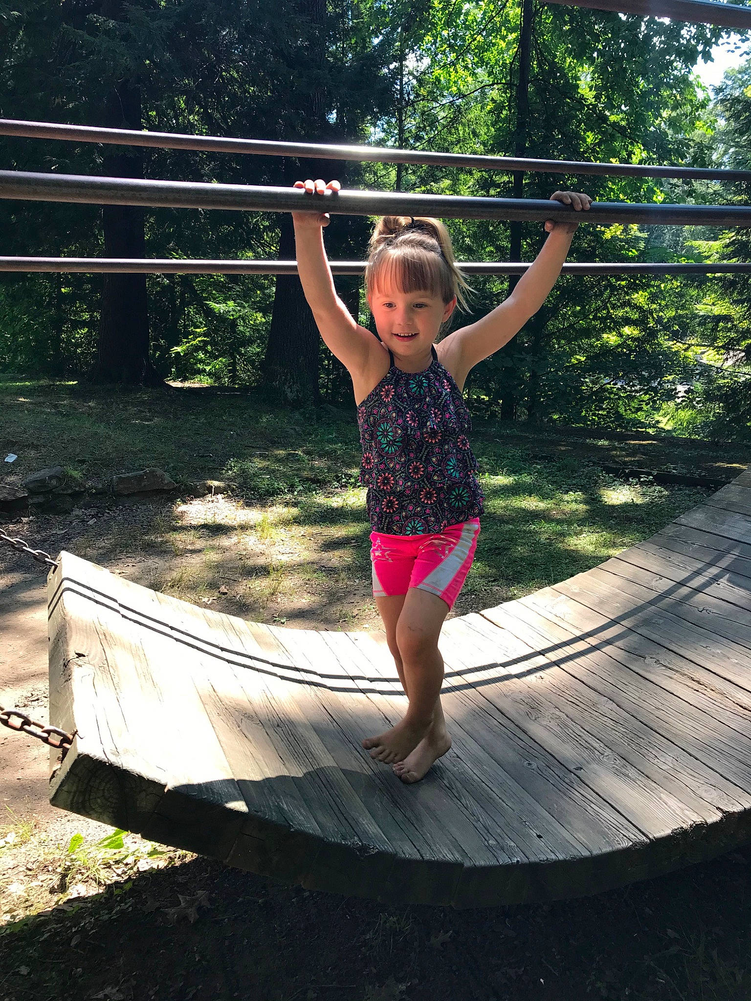 Mackenzie is registered to the contest to win money with this photo: balance, barefoot, child, fun, grass, happy, joy, leisure, outdoor_play_equipment, people_in_nature, person, plant, play, recreation, shade, smile, t_shirt, tints_and_shades, toddler, tree