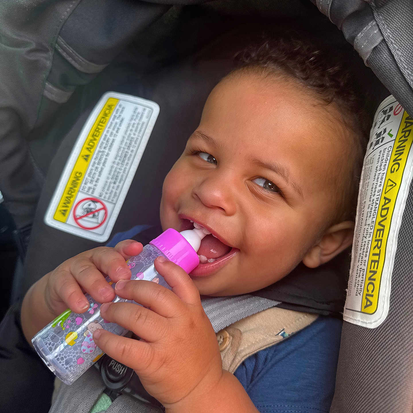 Atreveis is registered to the contest to win money with this photo: baby, bottle, car_seat, child, closeup, curly_hair, cute, drinking, face, hand, happy, indoors, infant, person, playful, safety, seatbelt, smiling, toddler, warning_label
