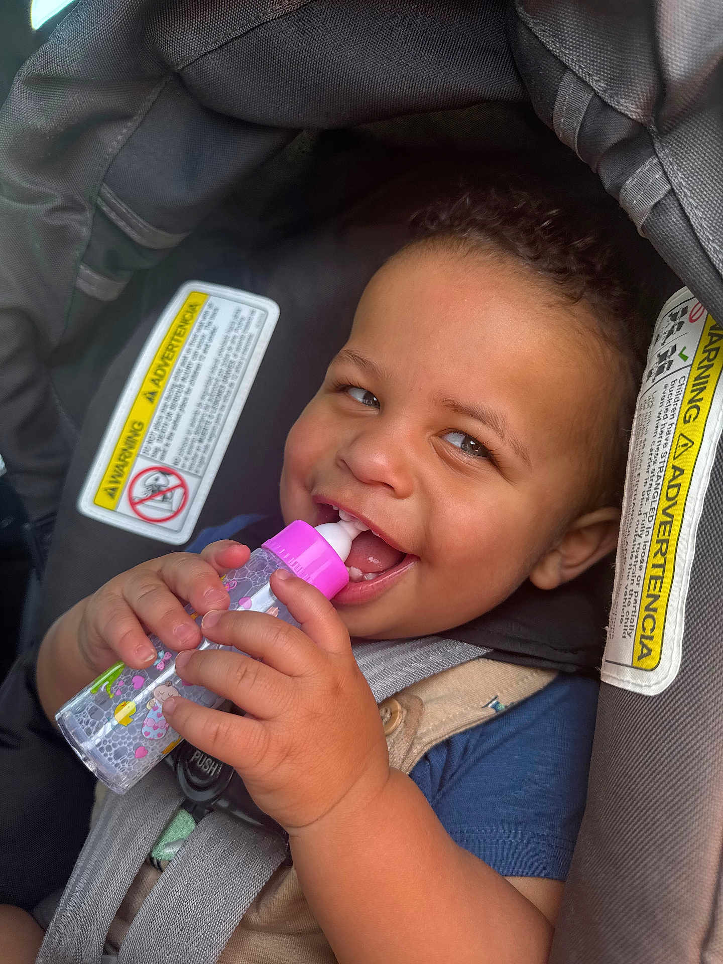 Atreveis is registered to the contest to win money with this photo: toddler, baby, car_seat, bottle, smiling, child, curly_hair, happy, seatbelt, warning_label, hand, face, cute, infant, indoors, closeup, safety, person, drinking, playful
