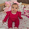 baby, child, pink_clothing, headband, bow, smiling, sitting, blanket, hearts, stuffed_toys, doll, pillow, bed, wooden_headboard, cute, indoors, happy, infant, portrait, cozy
