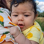 Estelle joined the competition — help win amazing prizes! adult, baby, child, closeup, curly_hair, daylight, expression, face, glasses, hand, holding, infant, nature, outdoor, patterned_clothing, person, portrait, skin, sky, yellow_clothing