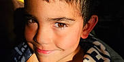 Christopher is registered to the contest to win money with this photo: child, boy, smile, face, brown_eyes, blanket, shadow, light, portrait, indoor, hair, skin, expression, young, cute, cozy, warm_light, close_up, happy, person