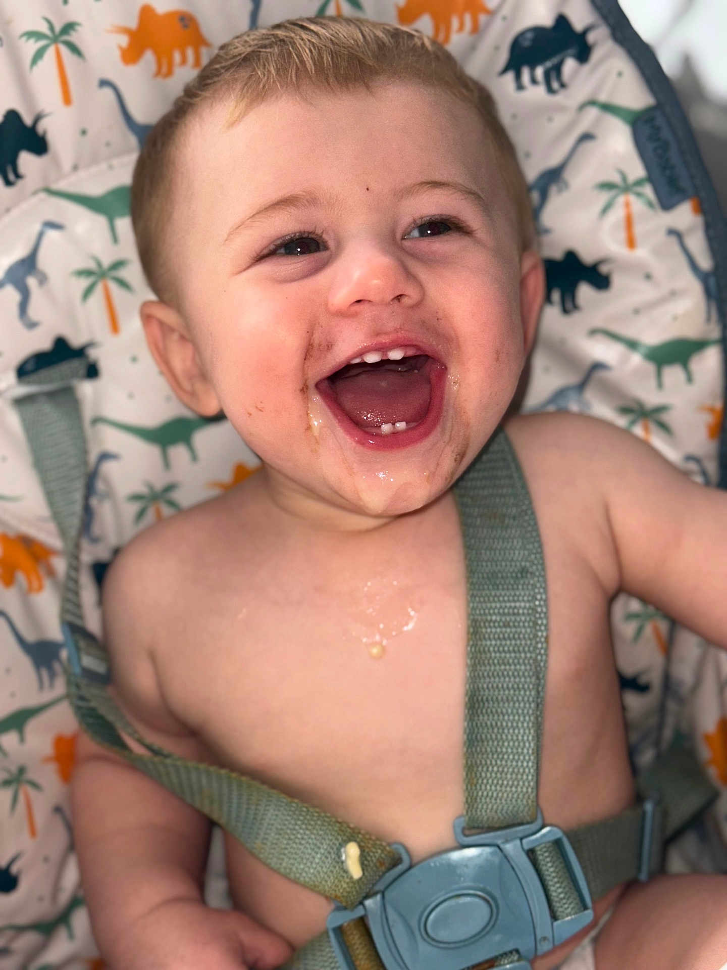 Hunter joined the competition — help win amazing prizes! baby, child, high_chair, messy_face, smiling, happy, dinosaur_pattern, seatbelt, toddler, mouth_open, food_smear, cute, infant, cheerful, indoor, portrait, straps, skin, face, closeup