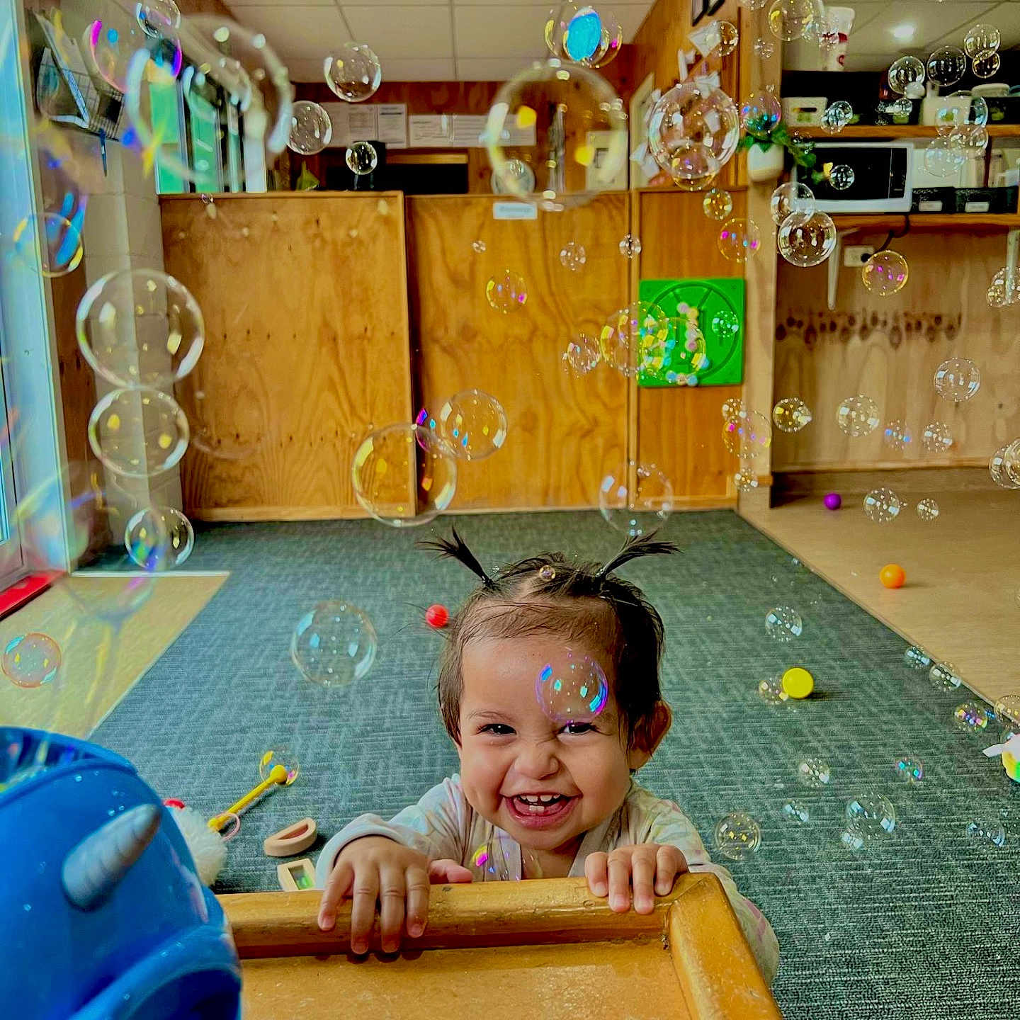 Te Atarangi is registered to the contest to win money with this photo: baby, bubble, carpet, child, childhood, colorful, cute, fun, hair_pigtails, happy, indoor, joy, person, play, playroom, smiling, table, toddler, toy, wooden_furniture