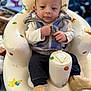 baby, infant, child, vest, knitted_booties, inflatable_chair, clothing, sitting, indoor, face, hand, zipped_jacket, comfort, cute, colorful, background_blur, expression, person, young, cozy