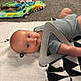 baby, infant, play_mat, toy, triangle_toy, carpet, floor, blue_eyes, smile, clothing, indoor, child, face, head, skin, cute, resting, colorful, soft, playtime