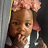 baby, car_seat, child, close_up, curious, cute, expression, face, fingers, flower, hand, headband, indoors, infant, person, portrait, safety_harness, seatbelt, skin, young