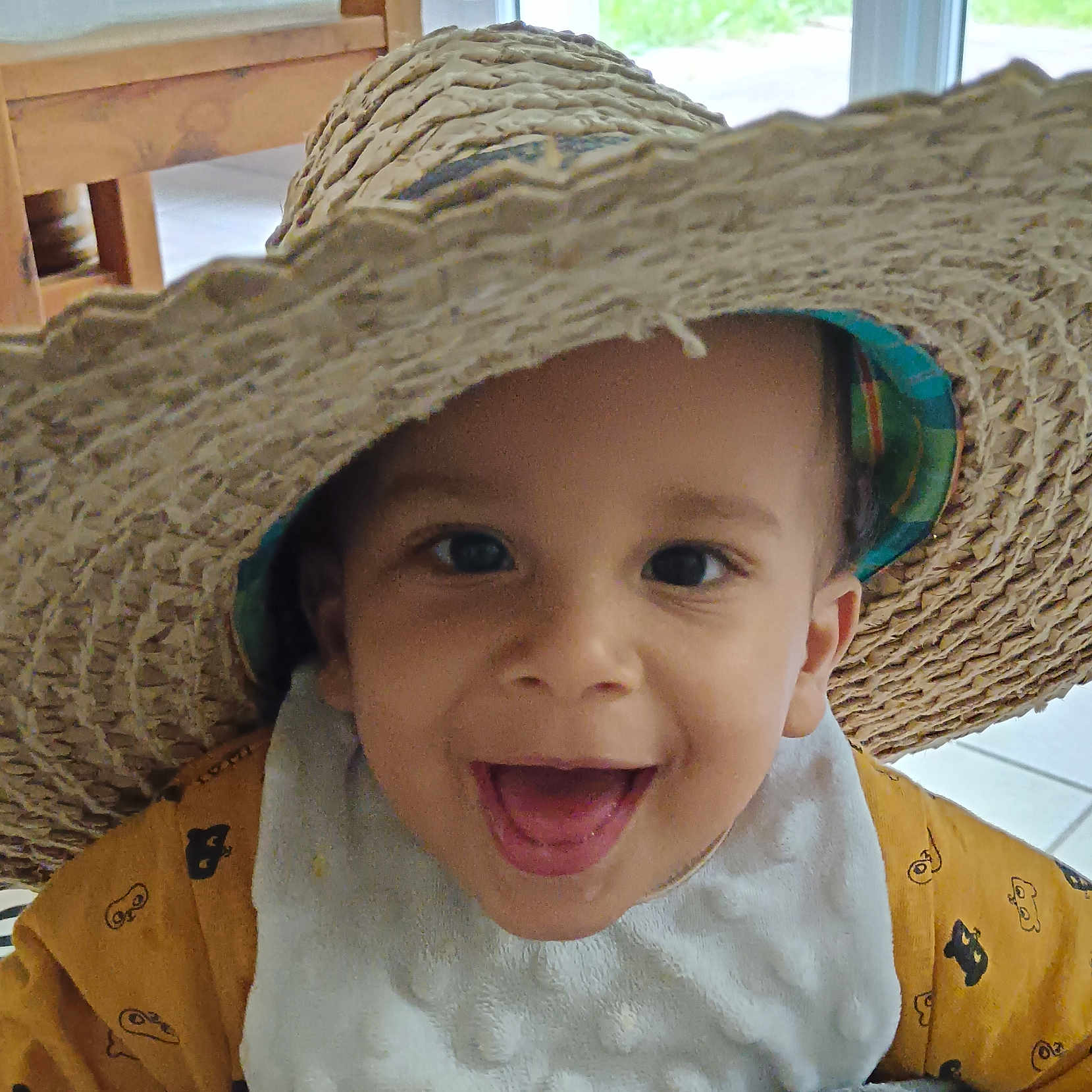 Tilyann'H a rejoint le concours — aidez-le/la à gagner de superbes lots ! baby, bib, child, closeup, cute, expression, face, floor, happy, hat, headwear, indoor, person, portrait, smiling, straw_hat, tile_floor, toddler, wooden_chair, yellow_clothing