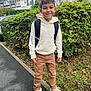 Lyham a rejoint le concours — aidez-le/la à gagner de superbes lots ! child, boy, smiling, hoodie, backpack, pants, sneakers, sidewalk, hedge, grass, urban, outdoor, casual, street, young, person, daylight, greenery, happy, standing