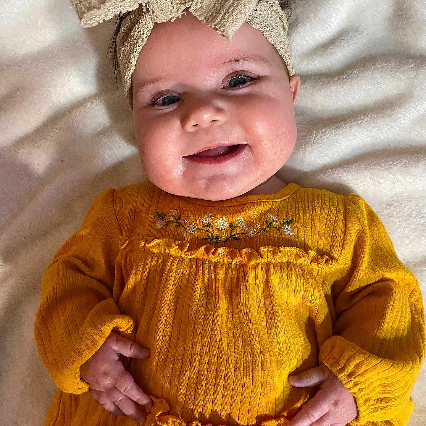 Adaire is registered to the contest to win money with this photo: baby, blanket, bow, child, chubby_cheeks, cozy, cute, face, floral_embroidery, hands, happy, headband, indoors, infant, lying_down, portrait, ribbed_clothing, smiling, soft_texture, yellow_dress