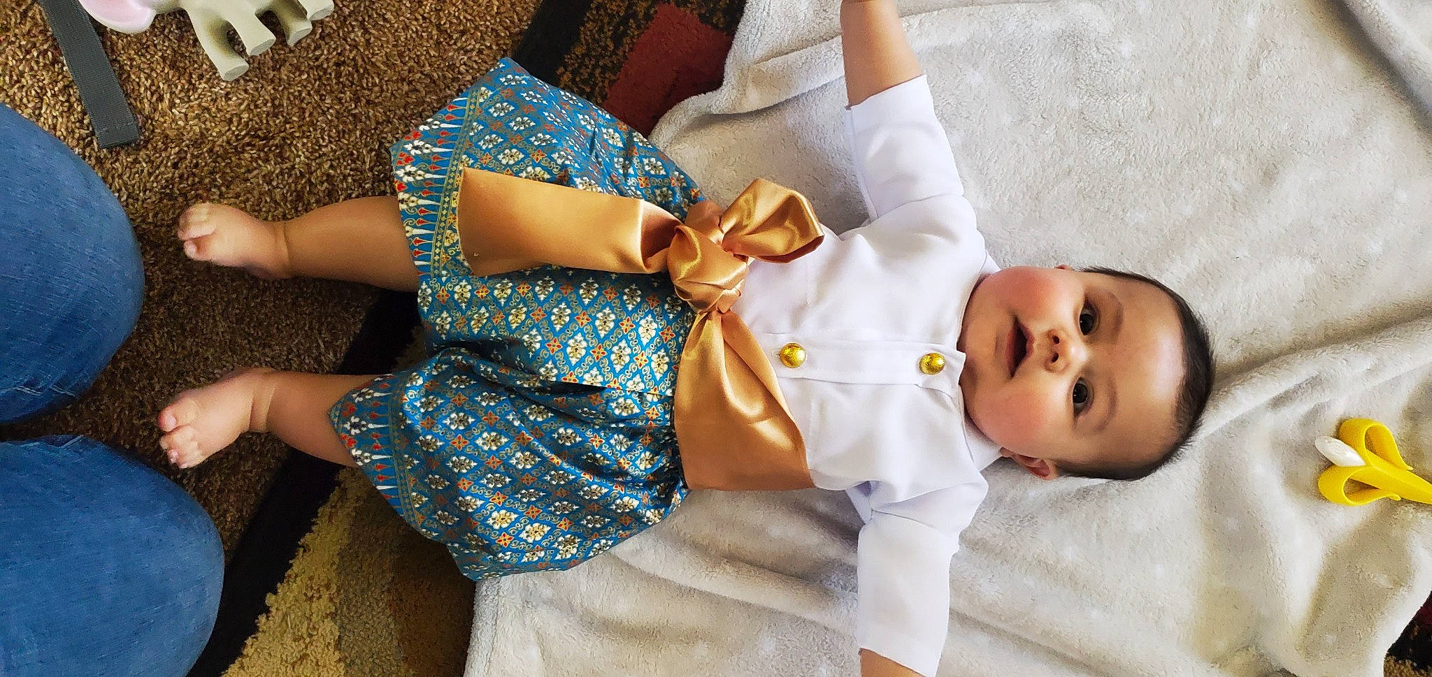 Christian is registered to the contest to win money with this photo: arm, baby, baby_toddler_clothing, comfort, day_dress, dress, finger, gesture, hand, happy, human_body, joint, neck, one_piece_garment, person, skin, sleeve, textile, thigh, waist