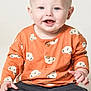 Rex is registered to the contest to win money with this photo: baby, child, smiling, sitting, orange_shirt, koala_pattern, blue_eyes, light_hair, barefoot, pants, cute, portrait, studio, happy, young, infant, casual_clothing, isolated, front_view, indoor