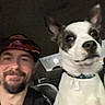 beard, black_patches, cap, car_interior, casual, collar, companion, dog, friendship, happy, indoors, man, night, pet, seat, selfie, smile, tattoo, white_dog, window