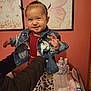 baby, bed, butterfly, child, clothing, cute, decor, denim_jacket, hands, happy, indoor, patterned_pants, person, pigtails, portrait, red_shirt, smiling, socks, toddler, wall_art