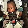 baby, car_seat, infant, mittens, booties, straps, safety, child, clothing, cute, dinosaur, expression, seat, young_child, indoors, person, head_support, black, white, gray