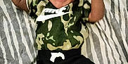 Kimani is registered to the contest to win money with this photo: baby, infant, crying, camouflage, nike, clothing, blanket, pattern, zebra_stripes, laying_down, person, young_child, expression, indoor, apparel, footwear, sock, cute, hands, face