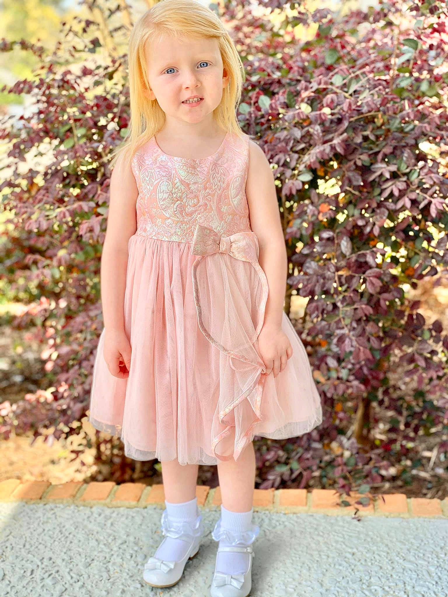 Hadley is registered to the contest to win money with this photo: bridal_party_dress, child, child_model, clothing, day_dress, dress, footwear, lace, pattern, peach, person, pink, plant, ruffle, shoe, toddler