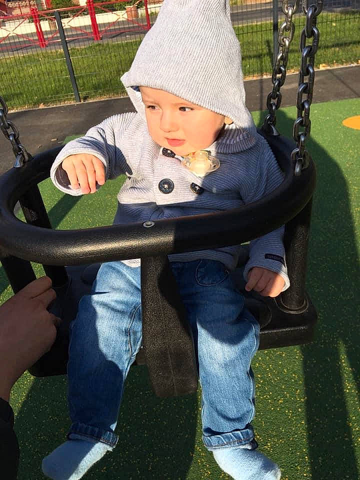 Mylan a rejoint le concours — aidez-le/la à gagner de superbes lots ! baby, child, city, denim, grass, headwear, human_settlement, jeans, leisure, outdoor_play_equipment, person, play, playground, public_space, recreation, sitting, swing, toddler