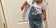 Janae joined the competition — help win amazing prizes! toddler, child, indoor, door, denim_overalls, rainbow_patch, hair_bows, pink_bow, blue_bow, sparkly_shoes, wooden_floor, white_door, smiling, standing, playful, cute, person, clothing, happy, young_child