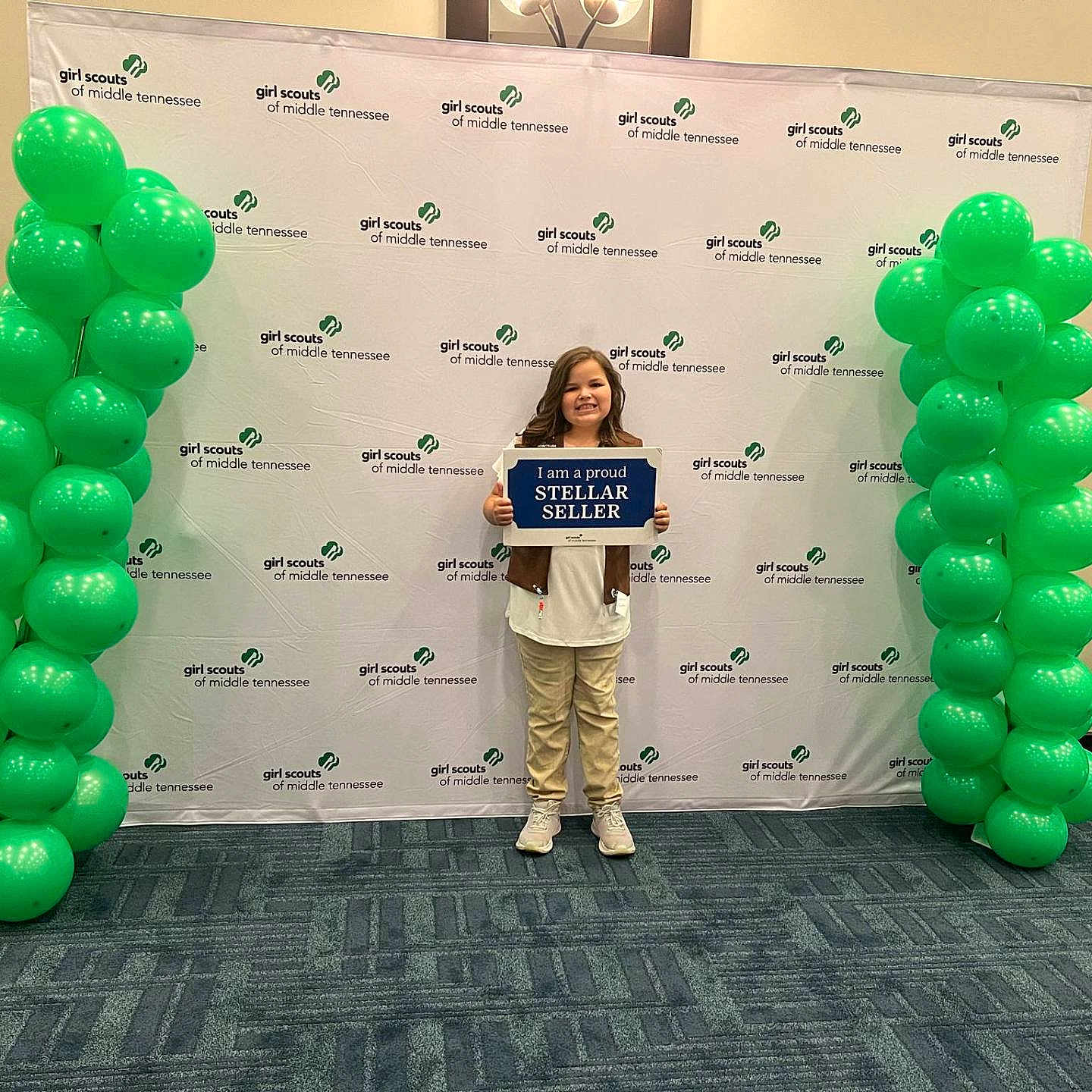 Ansley is registered to the contest to win money with this photo: adult, architecture, audience, balloon, building, clothing, crowd, face, female, footwear, head, number, person, shoe, speech, standing, student, symbol, text, woman