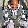 baby, child, stroller, smile, happy, toy, book, jacket, clothing, seatbelt, outdoor, sunlight, footwear, sock, person, infant, cute, play, baby_toy, baby_stroller