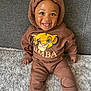 Noah is registered to the contest to win money with this photo: toddler, child, smiling, hoodie, brown_clothing, simba_print, sitting, carpet, couch, indoor, happy, cute, portrait, baby, face, person, cozy, casual_wear, expression, young_child
