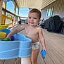toddler, child, smiling, diaper, water_table, toy, outdoor, deck, porch, wooden_floor, grill, furniture, daylight, play, happy, person, baby, summer, fun, casual
