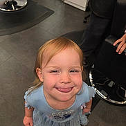 Oktober joined the competition — help win amazing prizes! child, girl, smiling, blue_dress, tongue_out, indoor, floor, tile_floor, hair, person, playful, happy, standing, furniture, chair, cable, closeup, cute, young_child, casual