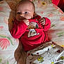 Killian is registered to the contest to win money with this photo: baby, infant, child, red_clothing, snoopy, patterned_pants, pillow, floral_pattern, cute, lying_down, indoor, soft_lighting, small_hands, face, wide_eyes, expression, blanket, resting, person, cozy