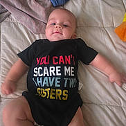 Killian joined the competition — help win amazing prizes! baby, infant, onesie, clothing, bed, blanket, fabric, person, child, cute, smile, face, skin, arm, leg, text_on_clothing, indoor, soft, comfortable, sleepwear