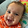 Azael joined the competition — help win amazing prizes! baby, infant, child, smiling, laughing, portrait, close_up, face, curly_hair, brown_hair, blue_eyes, orange_outfit, striped_clothing, fleece, seated, cushion, rainbow, sun_pattern, indoor, happy