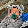 Lux is registered to the contest to win money with this photo: baby, pacifier, onesie, fuzzy_clothing, sleeping, child, person, outdoor, sidewalk, gravel, hand, blue_jacket, hood, ears, infant, close_up, cute, warm_clothing, portrait, peaceful