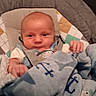 Carson is registered to the contest to win money with this photo: baby, blanket, blue, anchor_pattern, baby_seat, infant, cute, indoor, child, cozy, clothing, person, face, head, small_hands, soft_fabric, comfort, carrying_strap, seat, expression