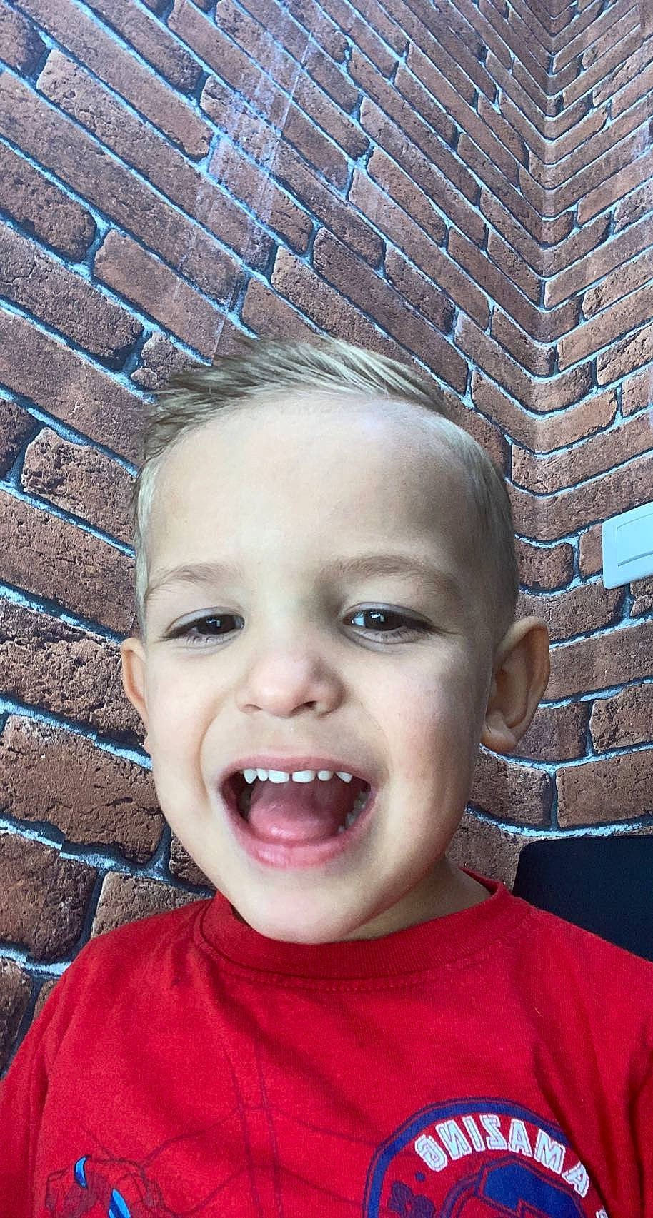 Luca participe au concours pour gagner de l'argent avec cette photo : blue, brickwork, cheek, chin, cool, eyebrow, eyelash, gesture, happy, head, human_body, iris, jaw, lip, mouth, nose, person, skin, toddler, tongue