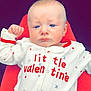 baby, infant, onesie, clothing, red, white, heart_pattern, face, expression, hand, fist, blue_eyes, skin, head, cute, portrait, child, sitting, young, indoors